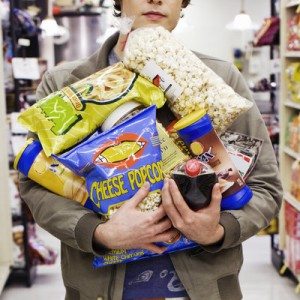 Young man holding armful of junk food